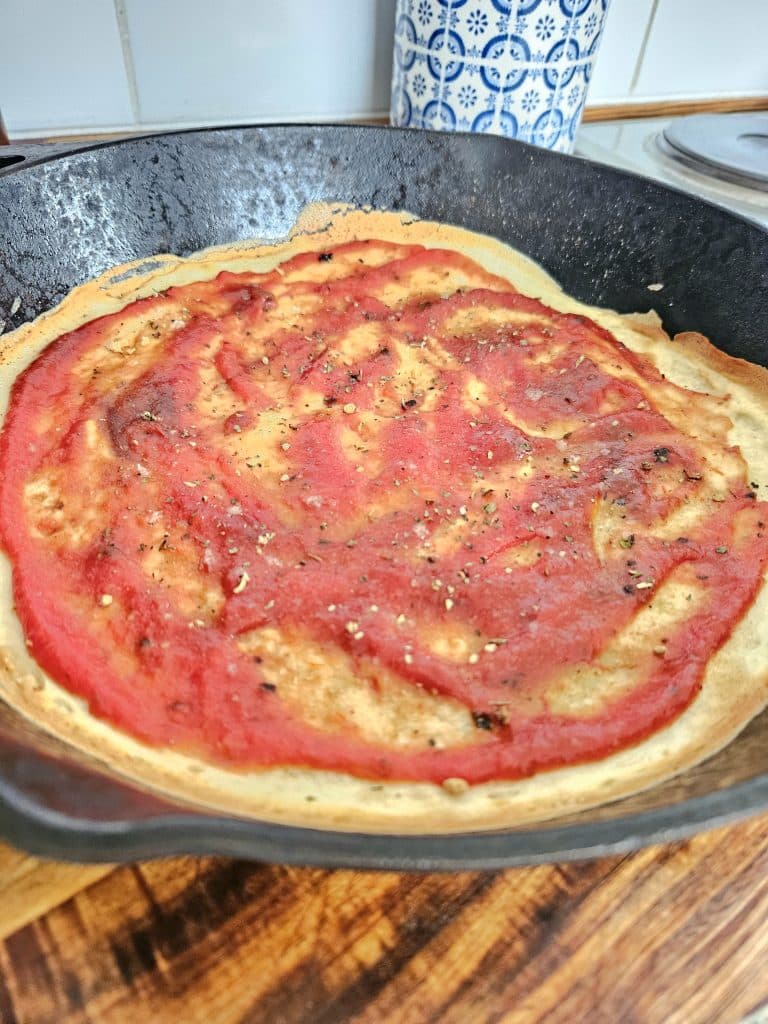 Sourdough discard pizza base topped with pasta sauce.