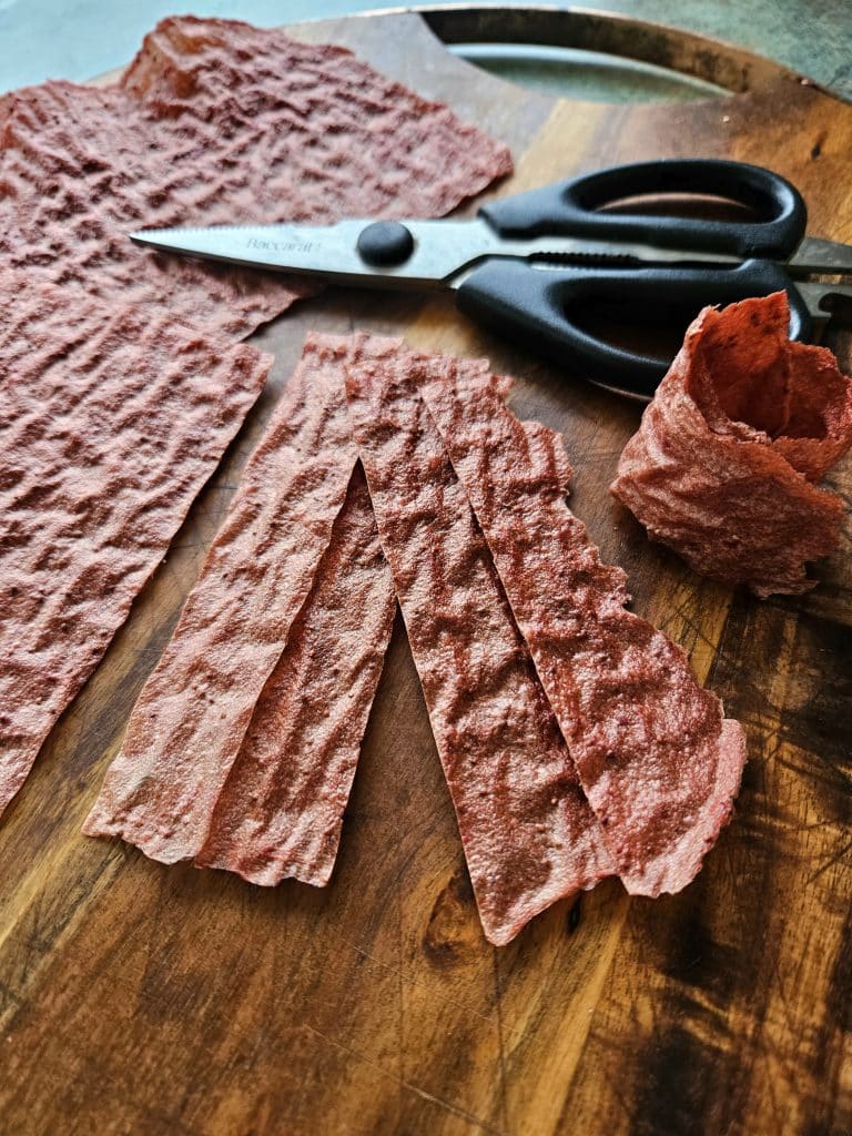 Scoby fruit leather being cut with scissors and rolled up. 