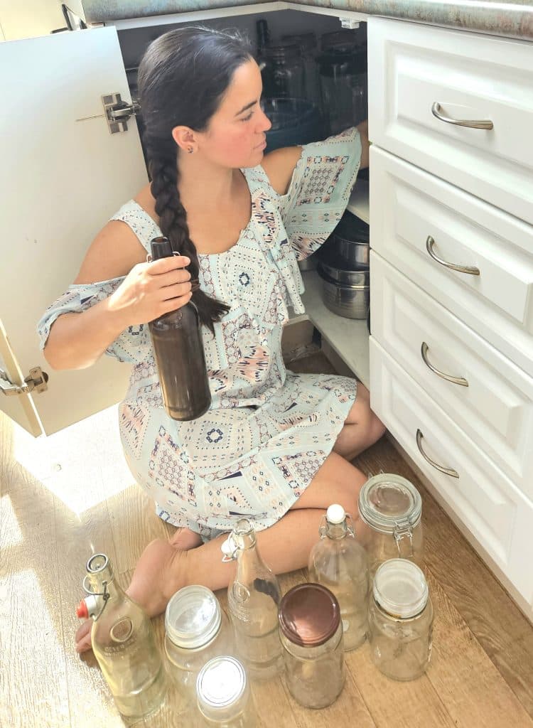 woman sitting on floor decluttering her kitchen cupboard.