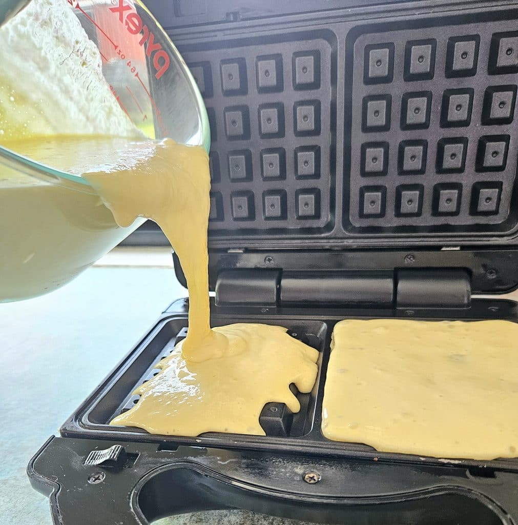 pouring Sourdough Waffle mix into a waffle maker.