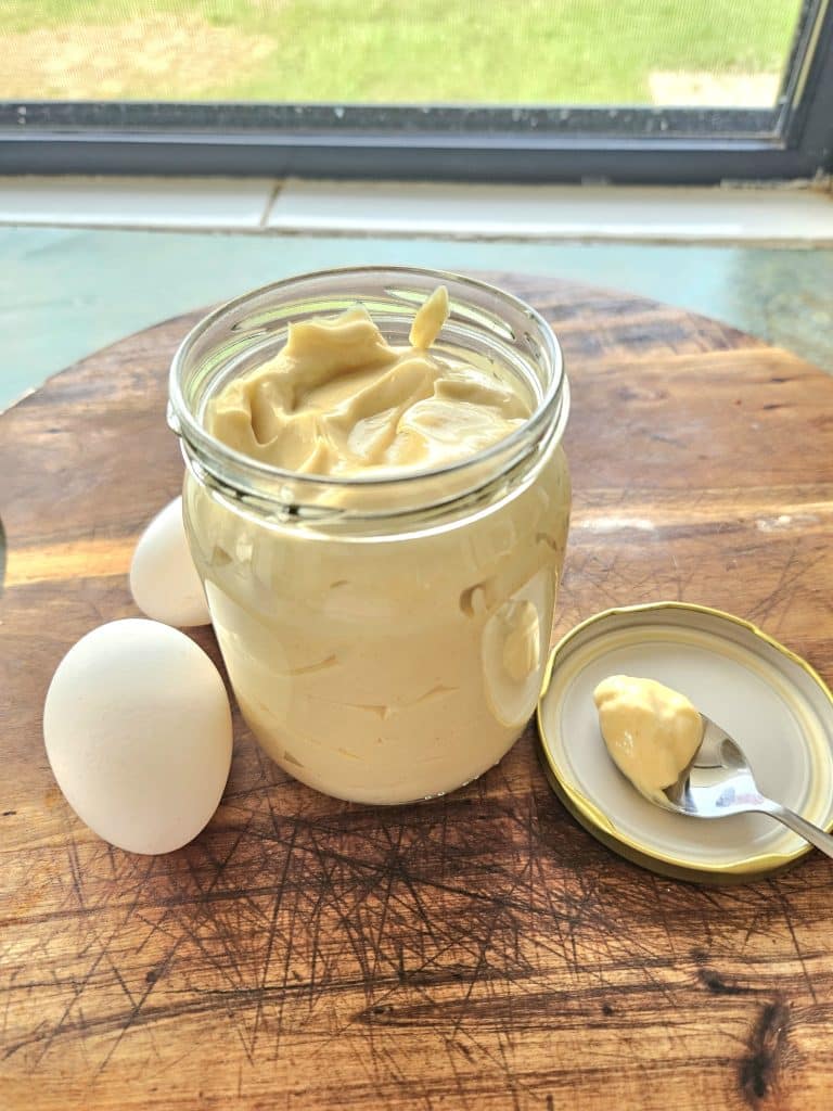 Homemade mayonnaise on a cutting board in a jar.