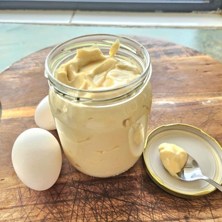 Homemade mayonnaise on a cutting board in a jar.