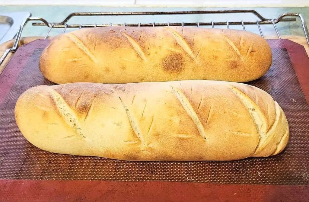 Two loaves of sourdough discard french bread on a silicon mat.