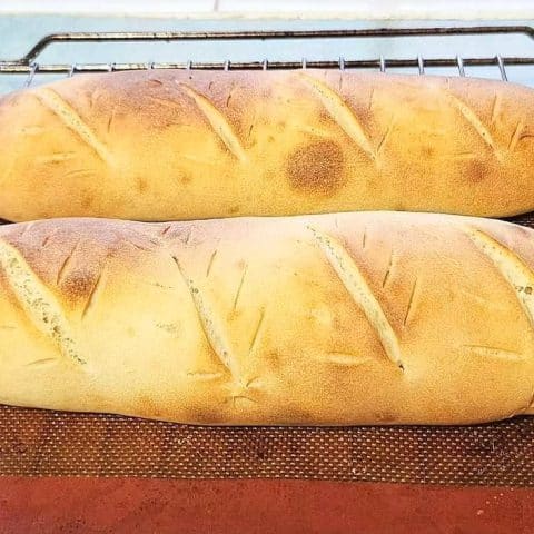 Two loaves of sourdough discard french bread on a silicon mat.