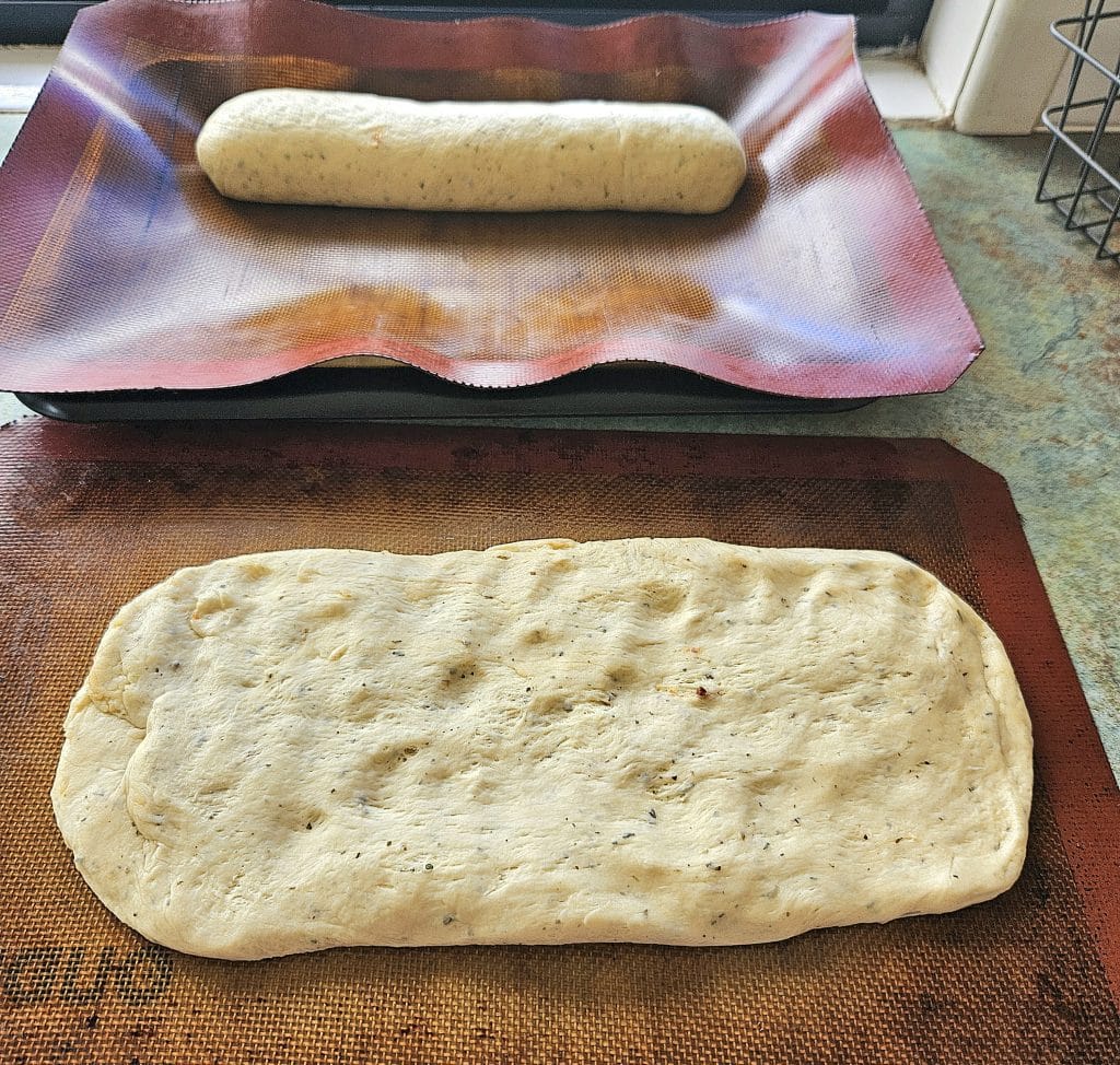 Sourdough discard french bread divided into two loaves and being shaped.