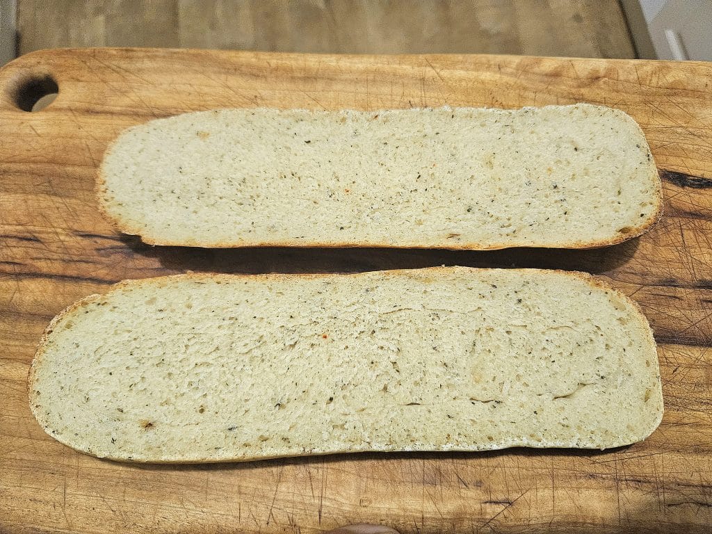 Sourdough French Bread cut in half on a cutting board.