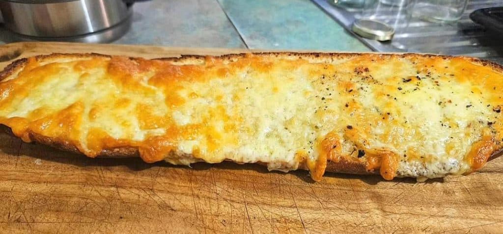 Cheesy sourdough garlic bread on a cutting board.