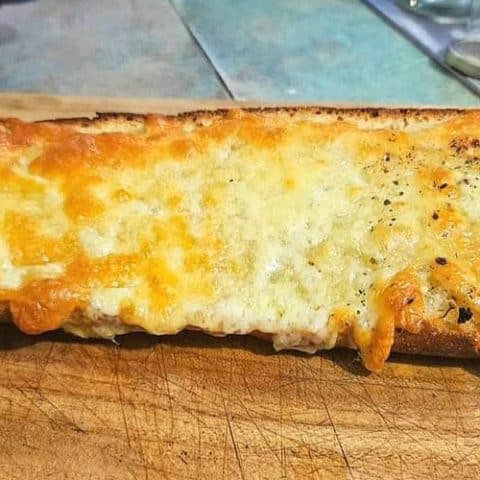 Cheesy sourdough garlic bread on a cutting board.