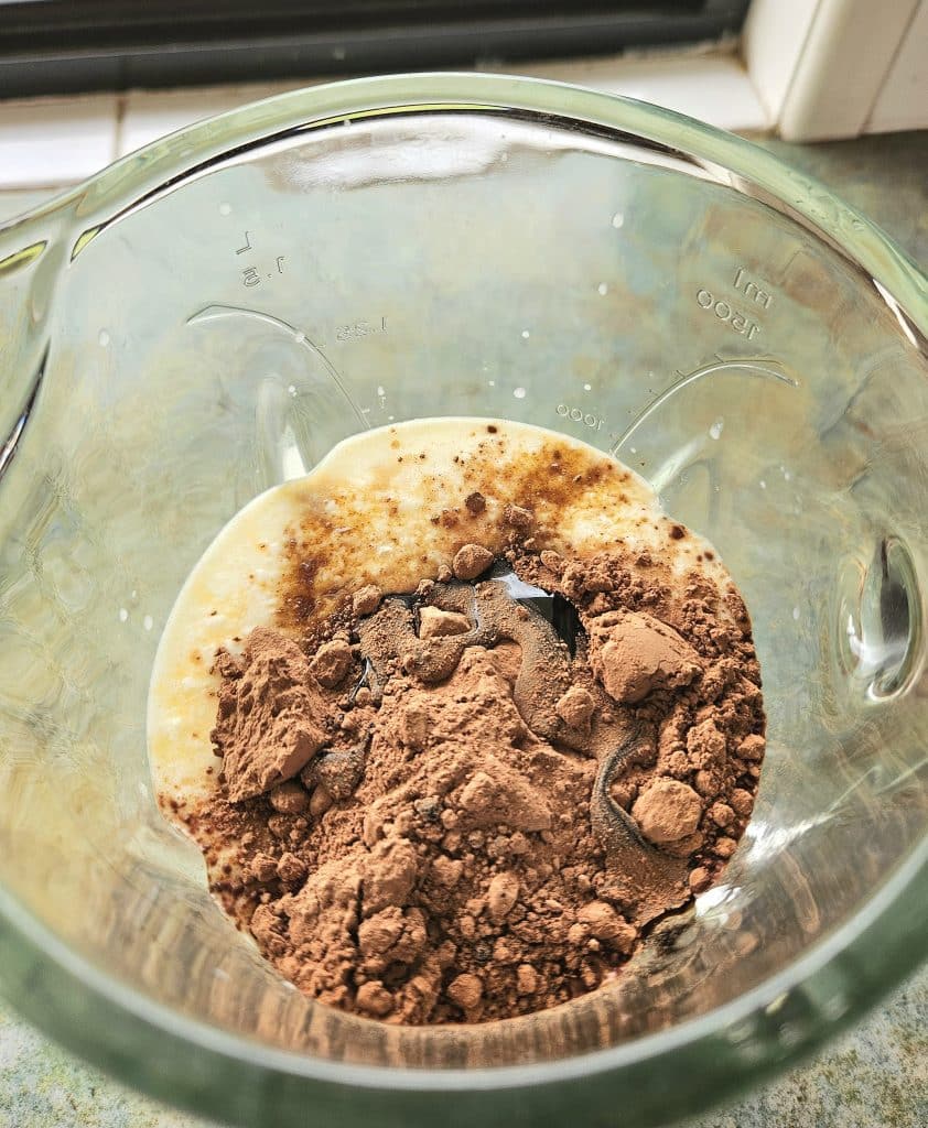 Chocolate avocado smoothie ingredients in a blender.