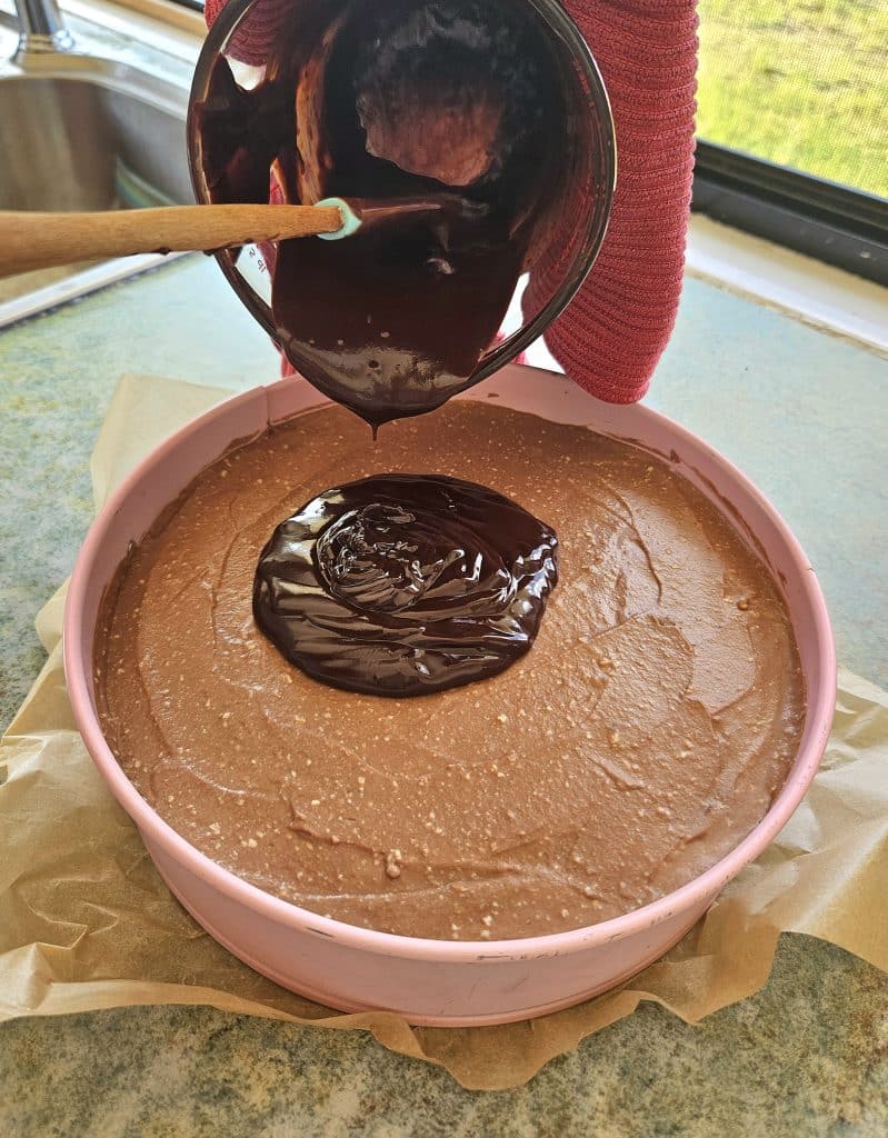 Pouring chocolate ganache on top of chocolate kefir cheesecake.