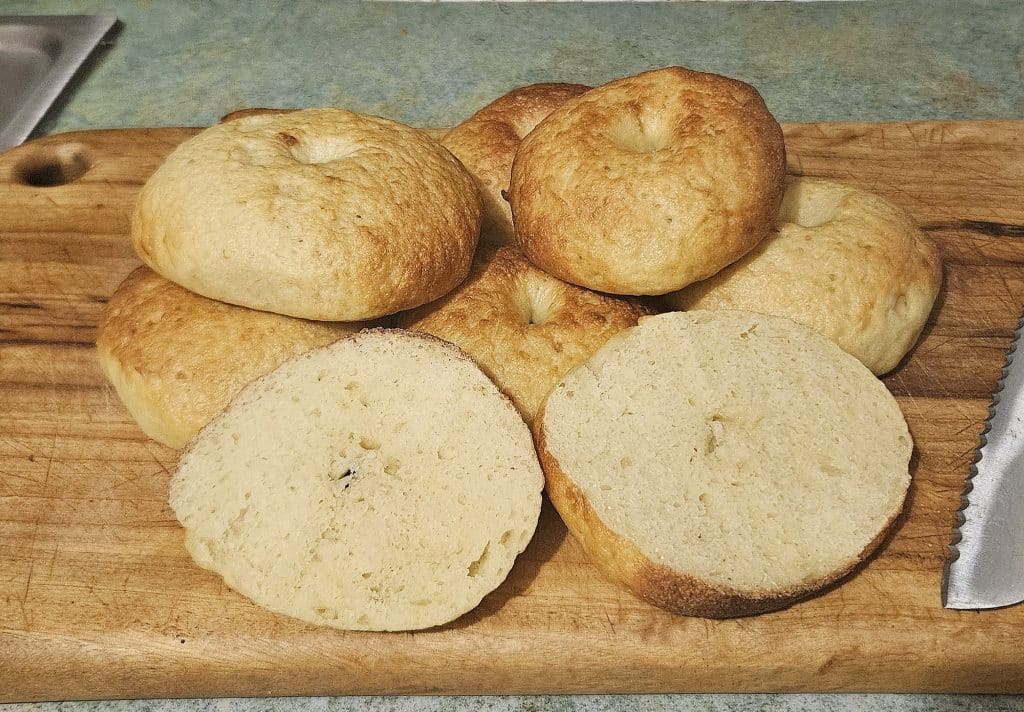 Soft homemade Sourdough bagels cut in half on a cutting board.