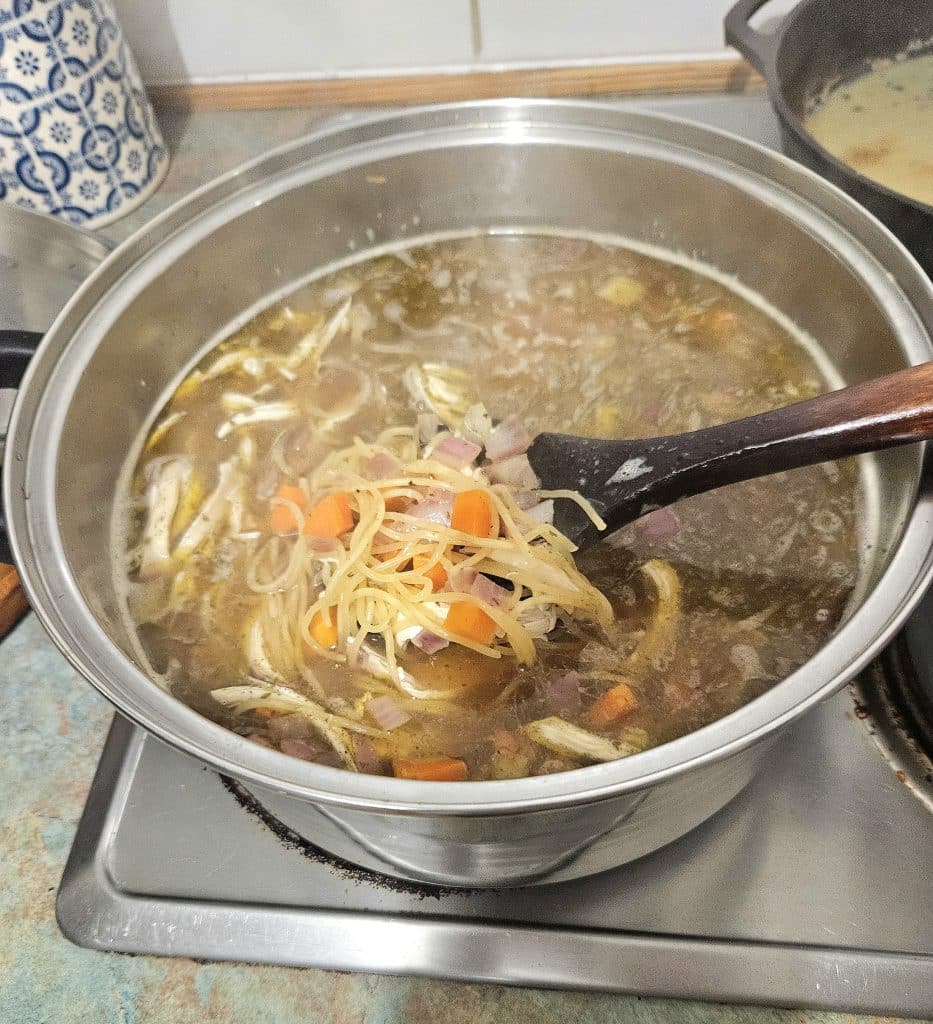 Broth, chicken and noodles cooking in a pot