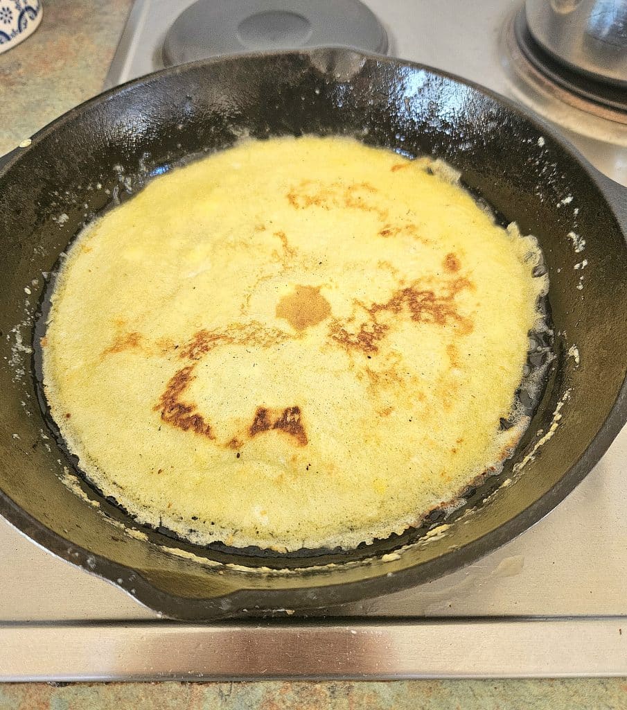 Sourdough discard crepe cooking in a pan.