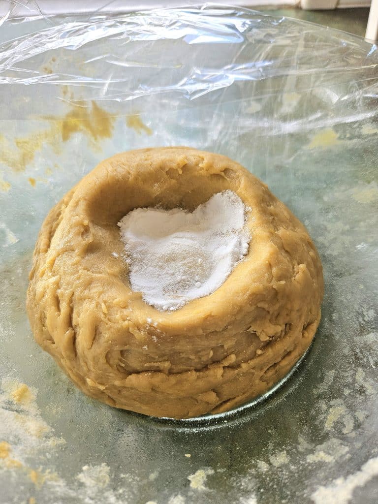 Adding baking soda to sourdough cinnamon roll ball.