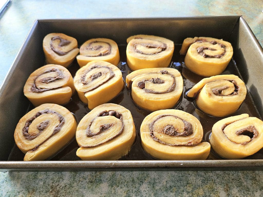 Placing sourdough cinnamon rolls in a pan.