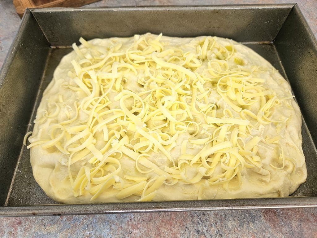 Shredded cheese on top of sourdough focaccia.