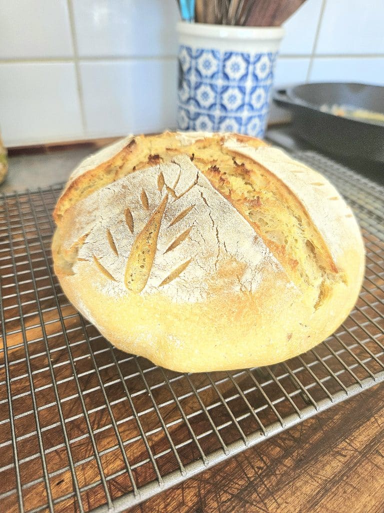 Easy sourdough artisan bread resting on a cooling rack.