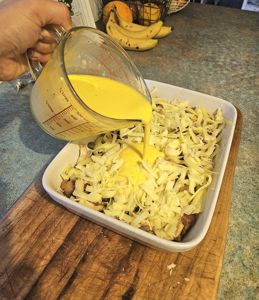 Pouring egg mixture into chicken quiche.