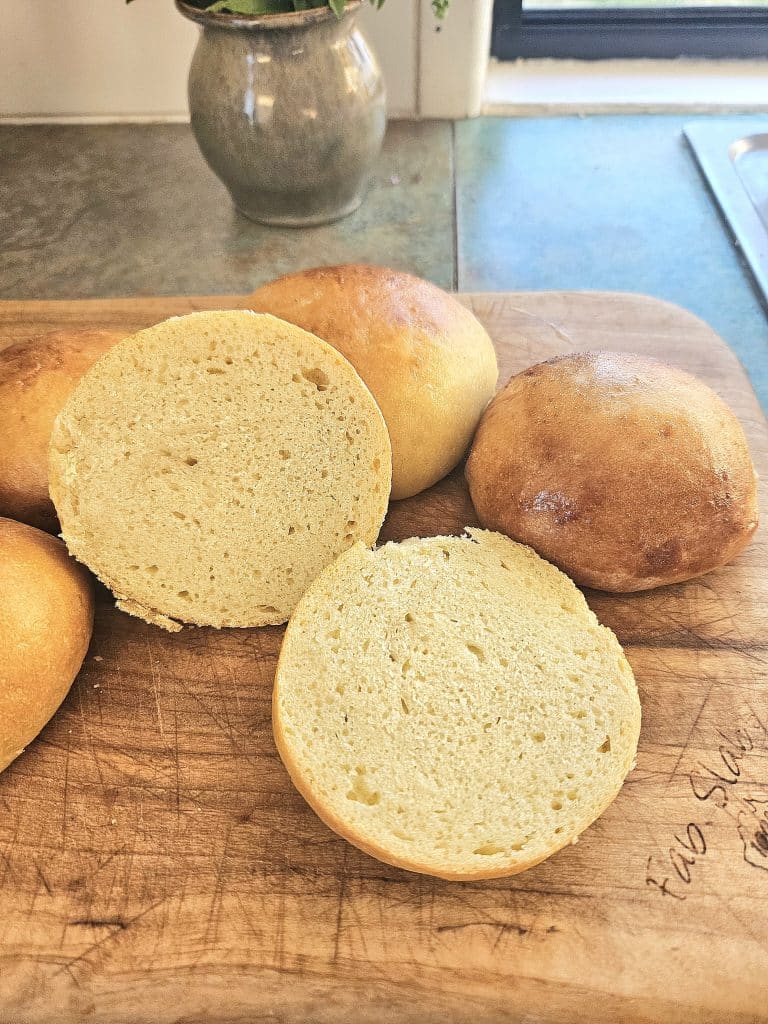 Sliced soft hamburger buns on a cutting board.