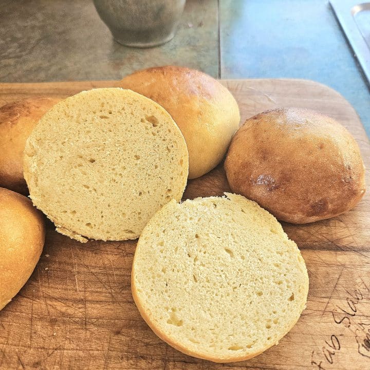 Sliced soft hamburger buns on a cutting board.