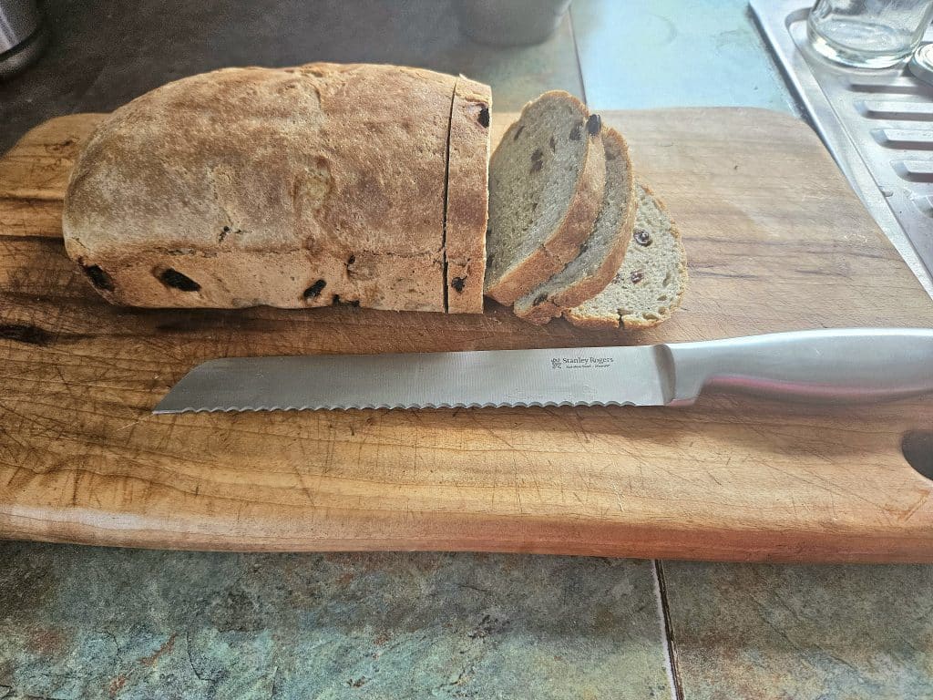 Slicing bread with a bread knife on a cutting board.