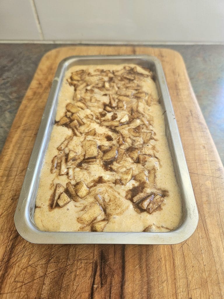 Sourdough discard apple loaf ready to bake in a bread pan.