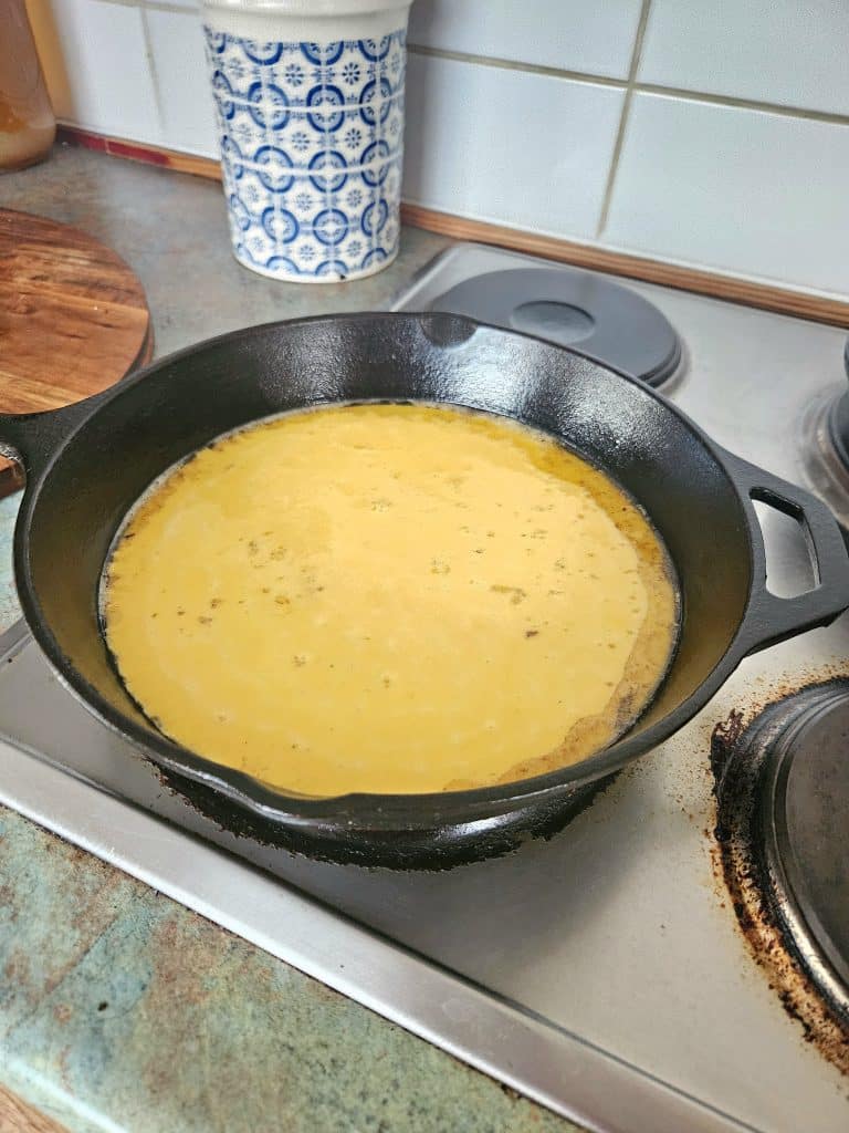 Cooking scrambled eggs on a cast iron pan.