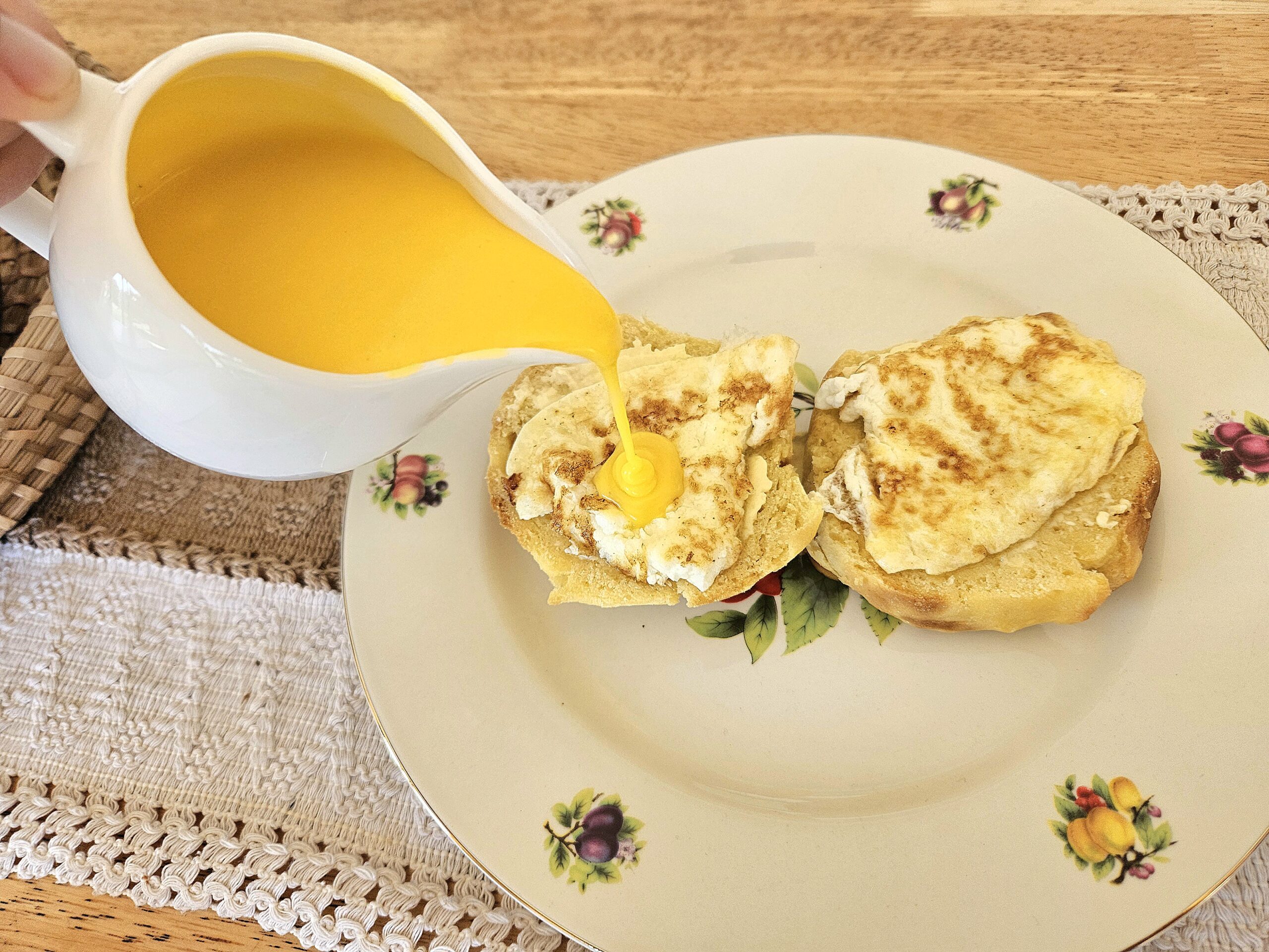 hollandaise sauce being poured onto eggs.