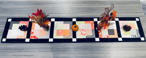 Homemade fall quilted table runner on a table.