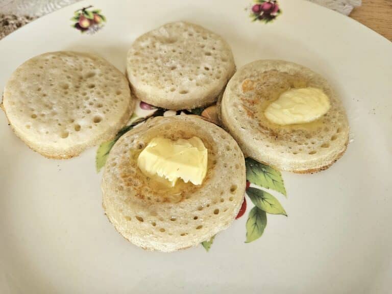 Fluffy sourdough crumpet on a plate with butter and honey.