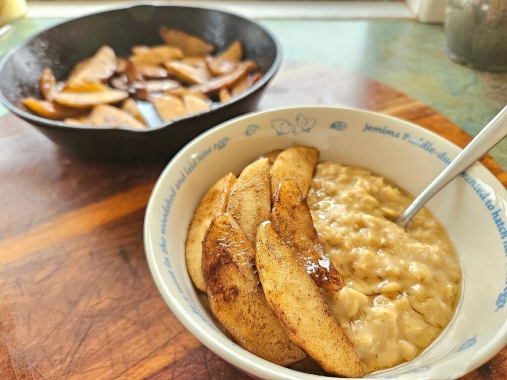 Creamy homemade oatmeal topped with stewed apples, in a bowl.