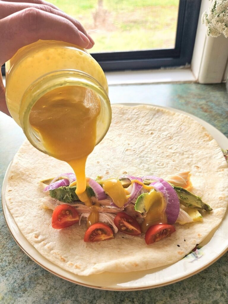 Pouring honey mustard on a wrap.