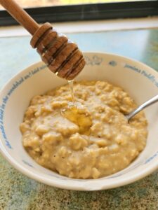 Homemade creamy oatmeal in a bowl topped with honey.