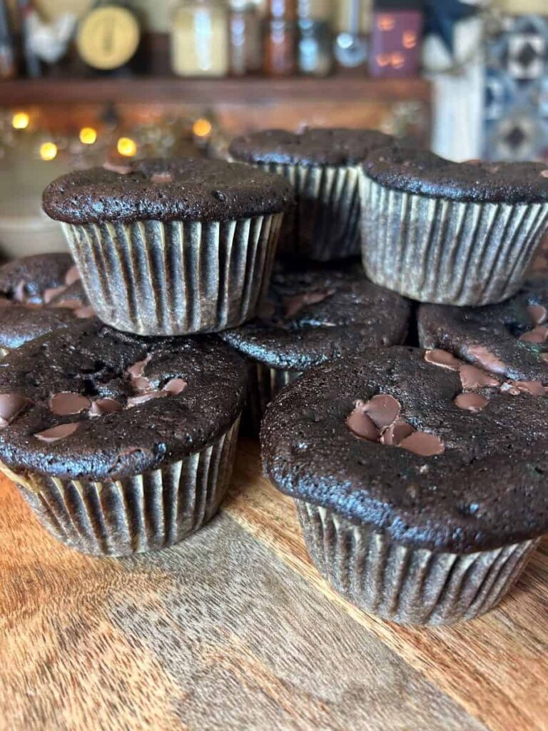 Chocolate pumpkin muffins stacked on top of each other on a table.