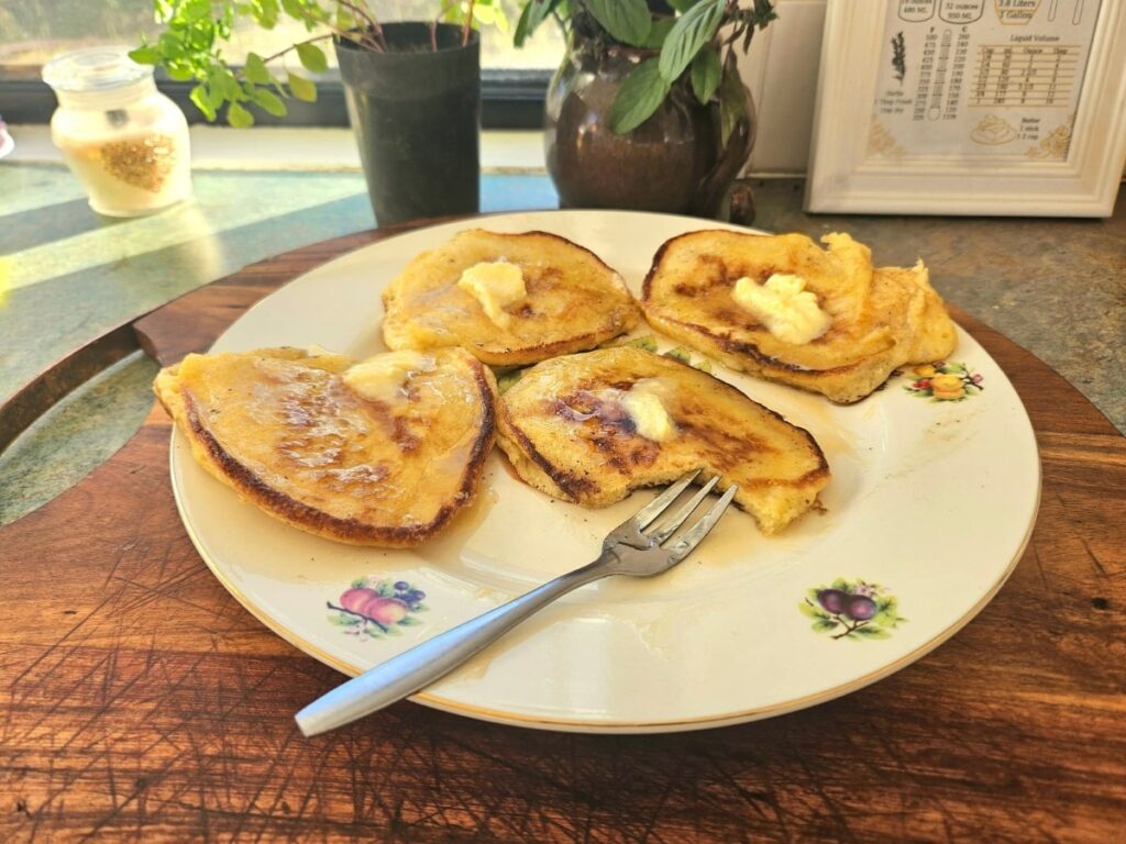 Soft sourdough discard pancakes on a plate with butter and syrup.