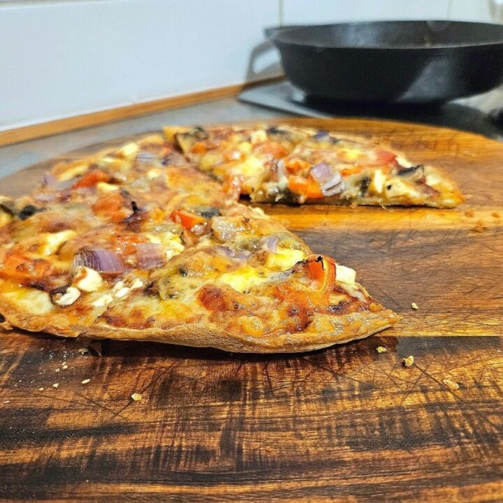 Delicious thin based sourdough pizza crust on a cutting board.