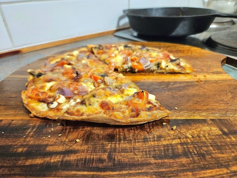 Delicious thin based sourdough pizza crust on a cutting board.