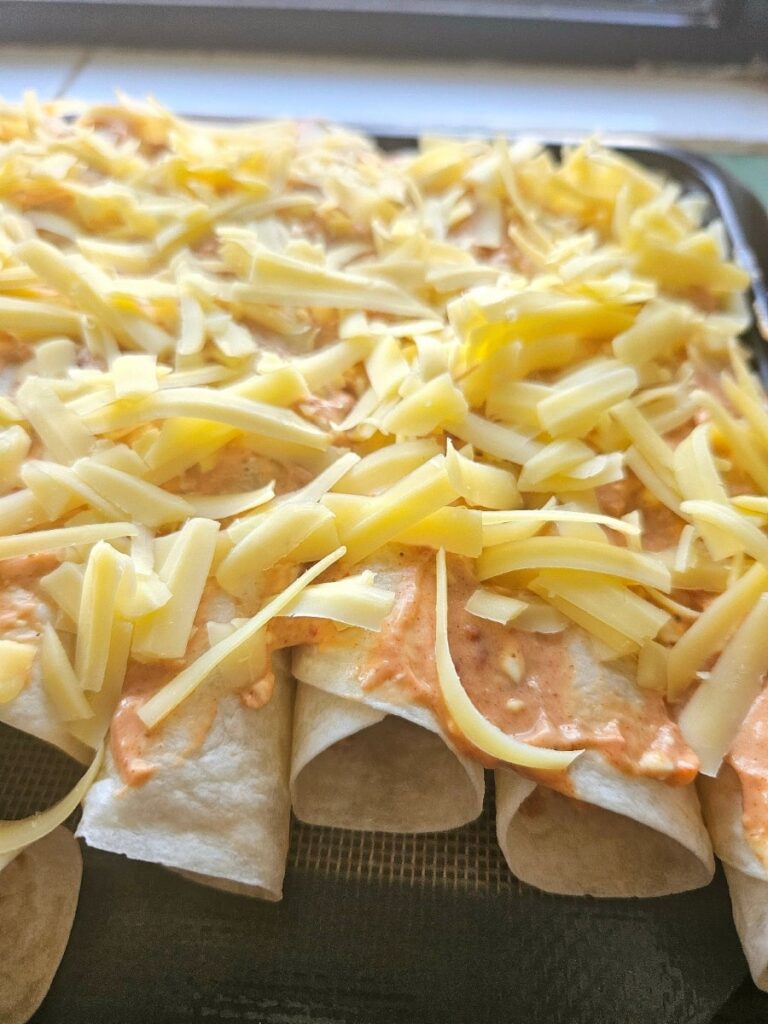 Homemade chicken enchiladas on a tray ready for baking.