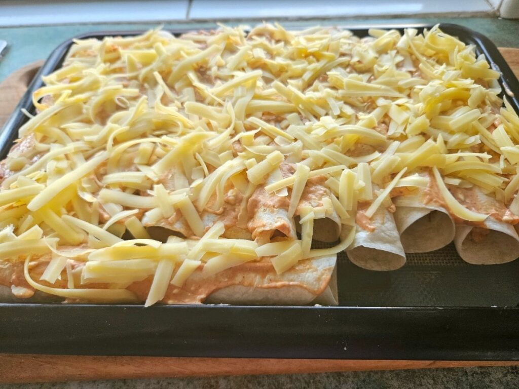 Enchiladas topped with enchilada sauce and cheese.