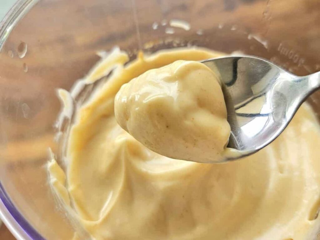 Thick homemade mayonnaise on a spoon.