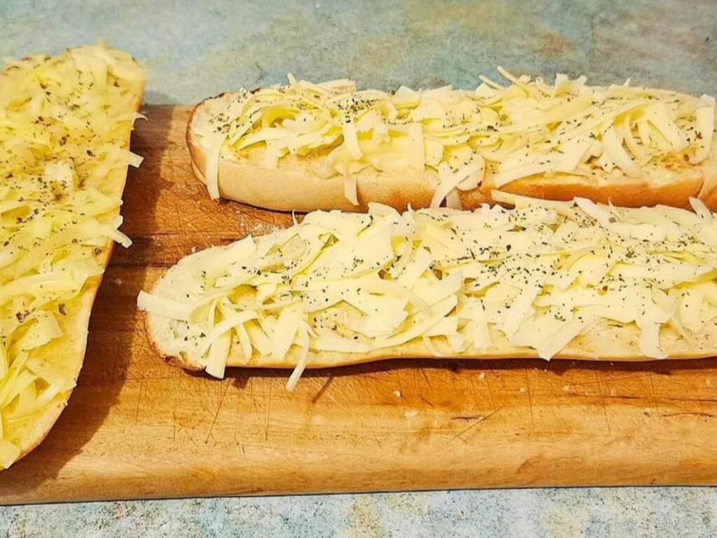 Cheesy garlic sourdough bread on a cutting board.