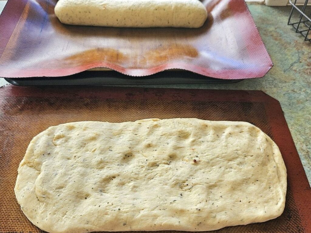 Flattening sourdough bread to turn into French bread.