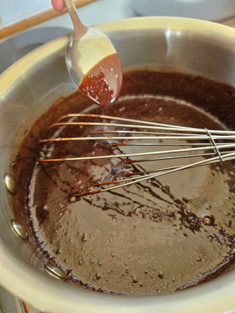 Homemade chocolate syrup being cooked in a pot.