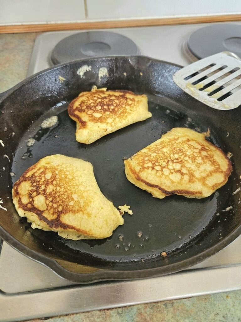 Cooking sourdough pancakes in cast iron pan.