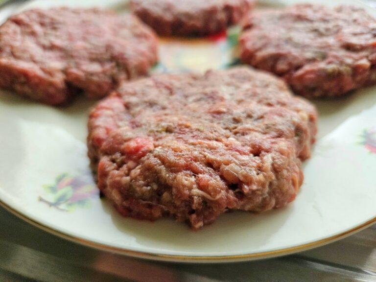 Homemade hamburger patty on a plate.