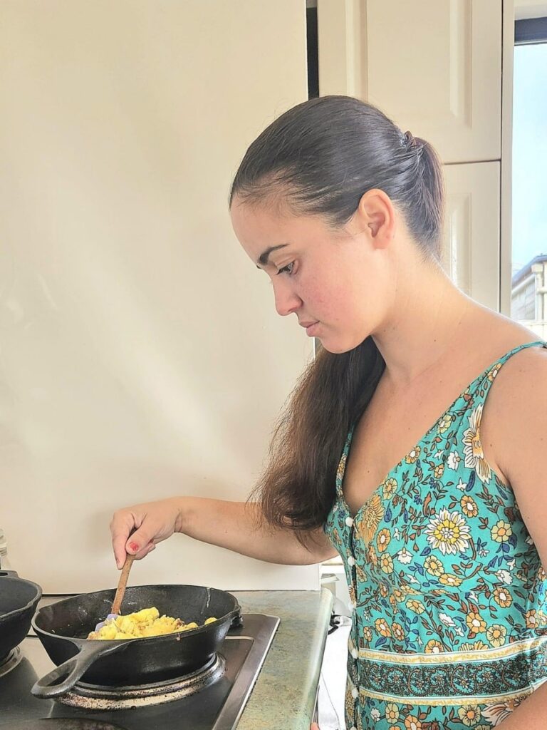 Homemaker cooking scrambled eggs on a cast iron skillet.