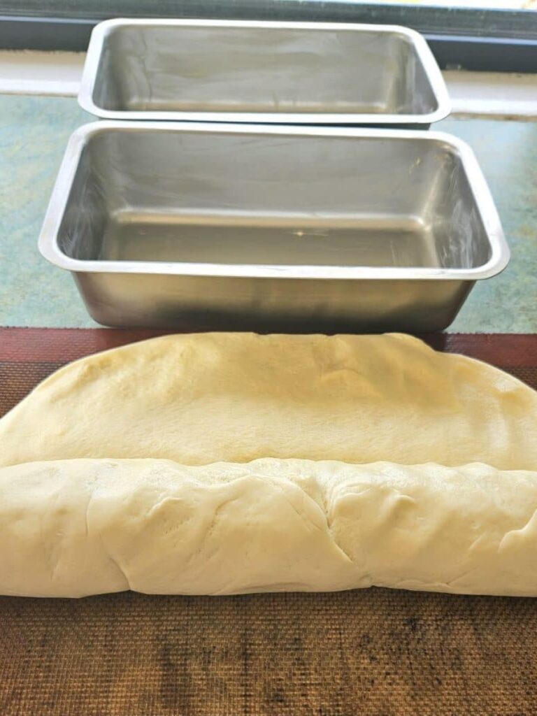 Flattening and rolling sourdough dough to make sandwich bread.