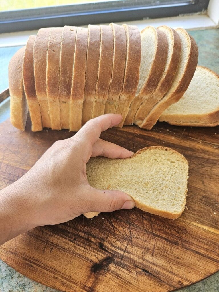 Soft sliced sourdough sandwich bread on a cutting board.