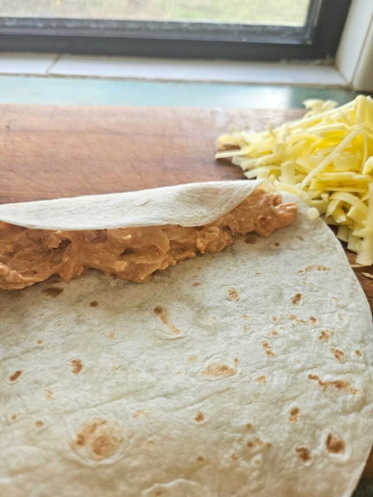 Rolling up chicken enchiladas.