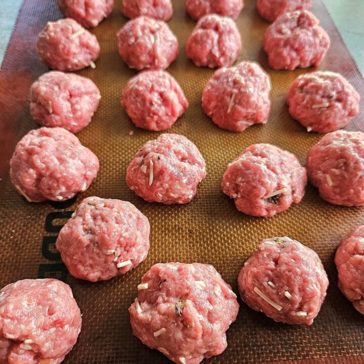 Homemade meatballs on a silicone matt ready to be baked.